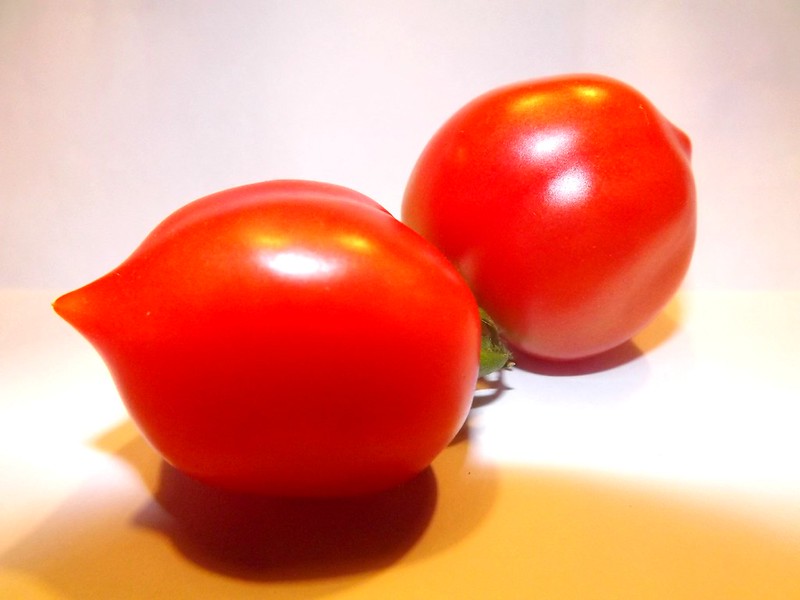 Two ripe red Principe Borghese tomatoes on a light background.